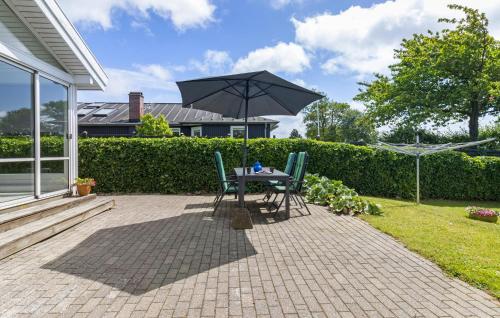 a table and chairs with an umbrella on a patio at 2 Bedroom Nice Home In Kerteminde in Kerteminde