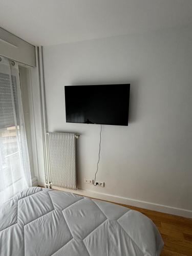 une chambre avec un lit et une télévision à écran plat au mur dans l'établissement T2 Boulogne Billancourt, à Boulogne-Billancourt