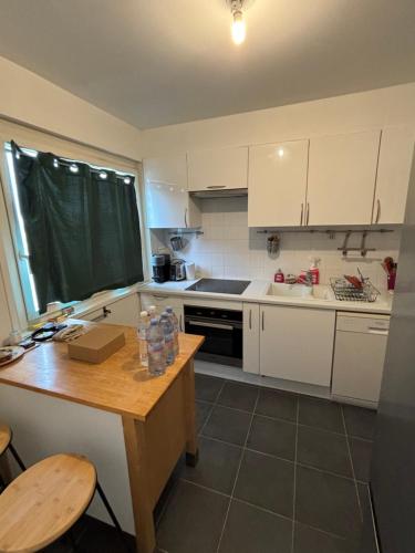 une cuisine avec des armoires blanches et une table en bois dans l'établissement T2 Boulogne Billancourt, à Boulogne-Billancourt