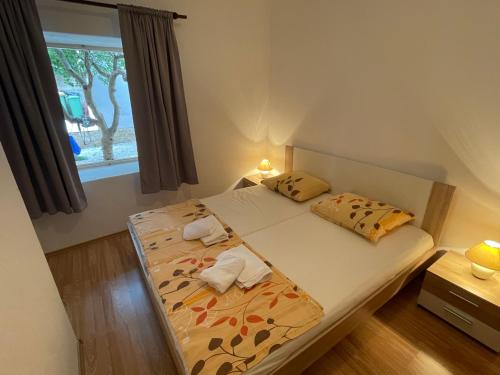 a bedroom with a bed with two pillows and a window at Apartmani Roko in Ražanac