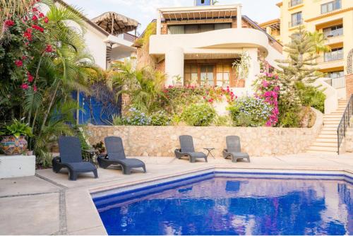 a house with a swimming pool with chairs and a building at Prime Cabo Stylish Studio Near Beach and Marina in Cabo San Lucas