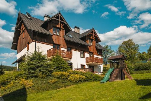 a large house on a hill with a playground at Ostoja Zaskalskie Apartament DIAMENT 100 m2, 56m2 in Jaworki