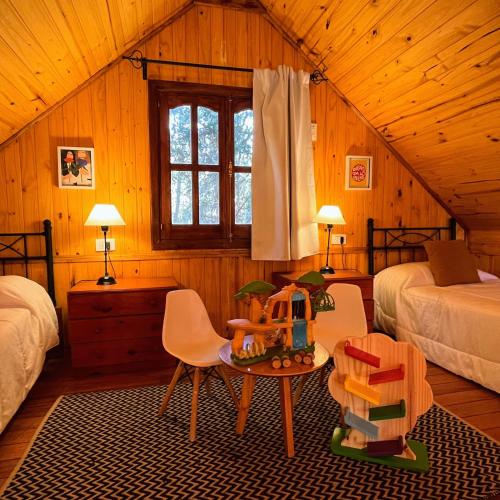 a bedroom with two beds and a table and chairs at Fratelli Cabañas-Apart in Rosario