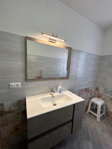 a bathroom with a sink and a mirror and a stool at Affittacamere "Fratello Sole e Sorella Luna" in Greccio