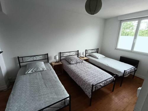 une chambre avec deux lits et une fenêtre dans l'établissement Gite de Paulette, à Pont-de-Briques