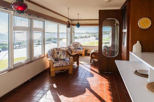 a living room with chairs and windows with a view at Coastal Sunset Paradise! Beach front & Ocean Views in Rockingham