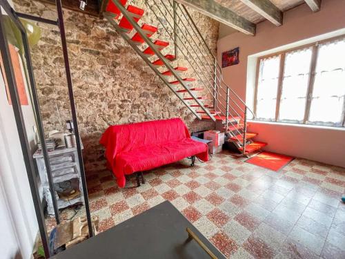 a living room with a red couch and stairs at Le Baki - Lac, randonnée, vue in Devesset