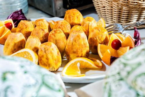 a table with plates of pastries and orange slices at Hotel Sirius in Taormina