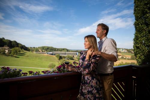 a man and a woman standing on a balcony with a glass of wine at Maria Theresien Hof Loipersdorf in Jennersdorf