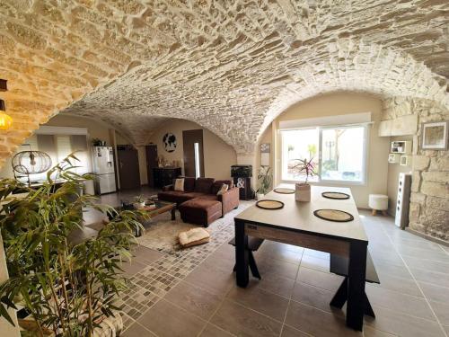 un salon avec une table et un mur en pierre dans l'établissement Maison avec jardin, à Vestric-et-Candiac