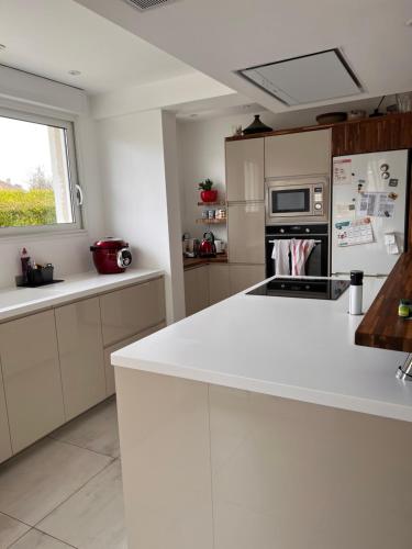 une cuisine avec des placards blancs et un comptoir blanc dans l'établissement Charmante chambre cosi, à Bretteville-sur-Odon