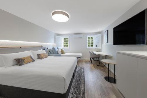 a bedroom with a white bed and a living room at Crowne Plaza Hawkesbury Valley by IHG in Windsor