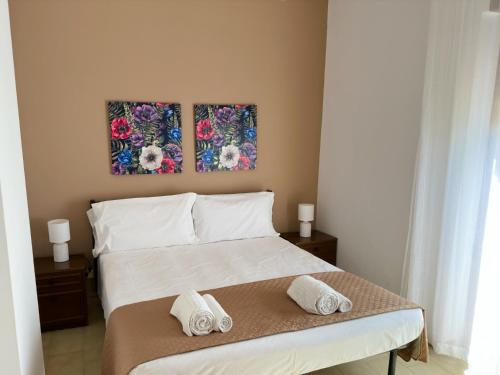 a bedroom with a bed with two pictures on the wall at Poseidon Bay Residence in Milazzo