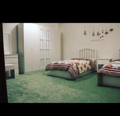two beds in a room with green carpet at Quba luxury in Medina