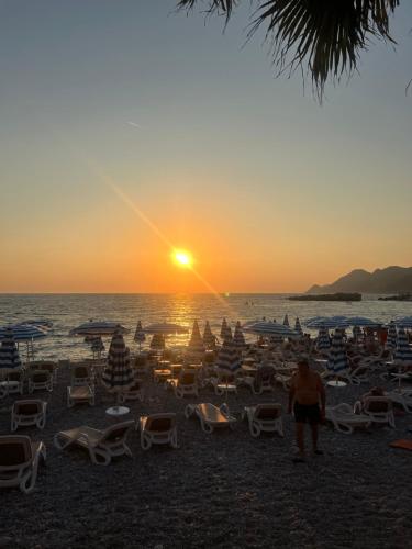 a beach with chairs and the sun setting at Oceans Apartman in Dobra Voda
