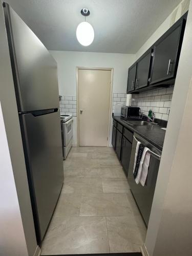 a kitchen with a stainless steel refrigerator and a hallway at Entire Apartment Prime Downtown location Free underground Parking in Calgary