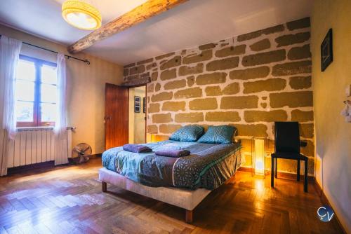 ein Schlafzimmer mit einem Bett und einer Steinwand in der Unterkunft Belle villa provençale - familiale - Grand terrain in Saint-Quentin-la-Poterie