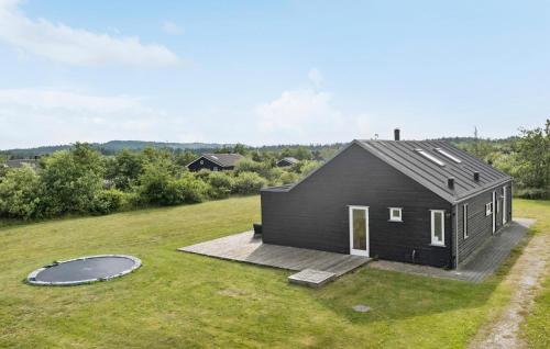 a black house with a deck and a trampoline at Holiday Home Kronvildtvej I in Brovst