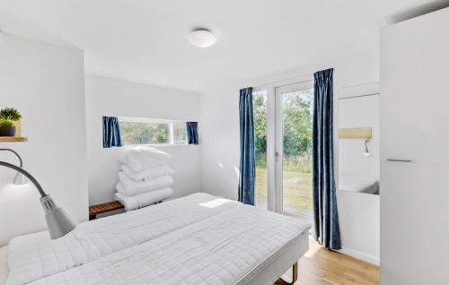a white bedroom with a bed and a window at Holiday Home Kronvildtvej I in Brovst