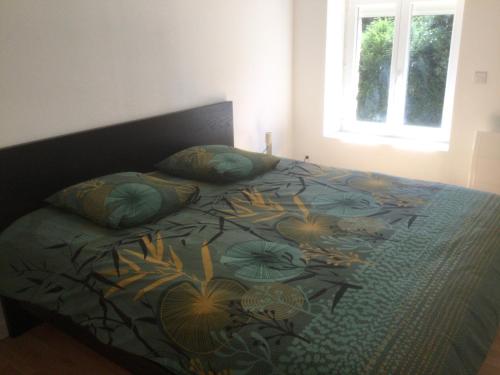 a bed with a blue comforter with flowers on it at La maison trémière in Clécy