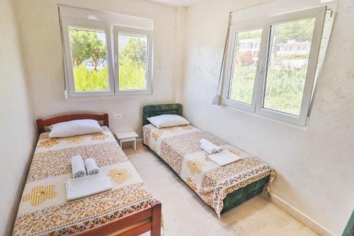 two beds in a room with two windows at Ratac Eco Guest House in Sutomore