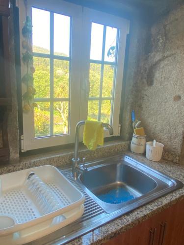 een gootsteen met een droogrek naast een raam bij Casa do Carqueijo in Vila Praia de Âncora