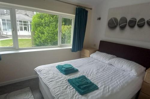 a bedroom with a bed with two green towels on it at Sunny holiday house in Newquay