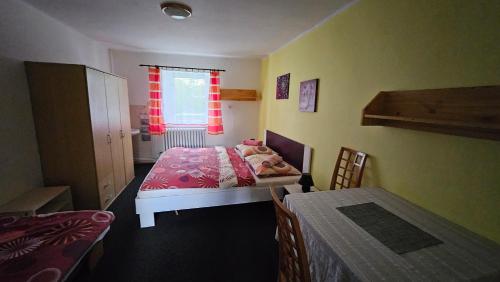 a small bedroom with a bed and a table at Penzion Tomy Pihlov in Horní Planá
