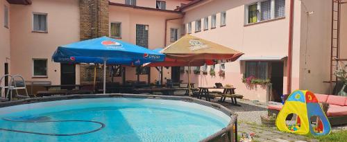 a swimming pool with an umbrella and a playground at Penzion Tomy Pihlov in Horní Planá