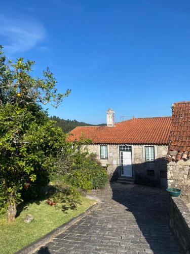 a stone house with a red roof and a driveway at Casa do Carqueijo in Vila Praia de Âncora
