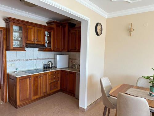 a kitchen with wooden cabinets and a table and a clock at Nikić Apartments in Ulcinj