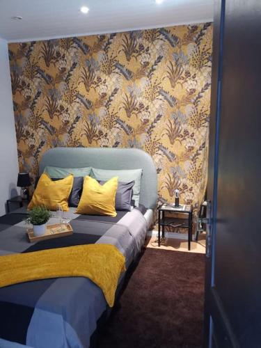 une chambre avec un lit avec des oreillers jaunes et du papier peint dans l'établissement mulhouse hyper centre, à Mulhouse