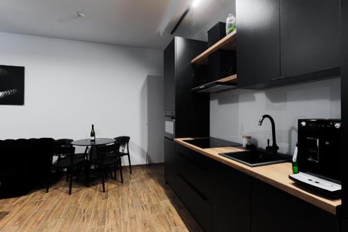 a kitchen with black cabinets and a table with chairs at Hedonia Apartamenty Premium in Opole