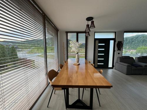 a dining room with a wooden table and a couch at Lazăr Home in TÄƒuÅ£ii MÄƒgheruÅŸ