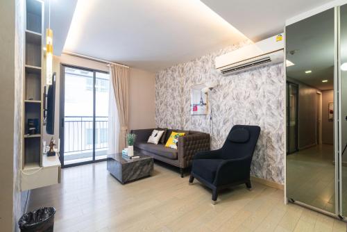 a living room with a couch and a chair at Dazzle Sukhumvit 7 by LeFoyer in Bangkok