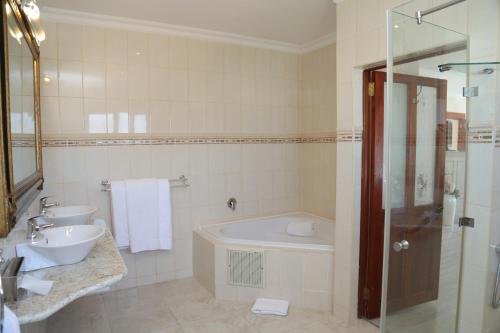 a bathroom with two sinks and a tub and a shower at Misty Waves Boutique Hotel in Hermanus