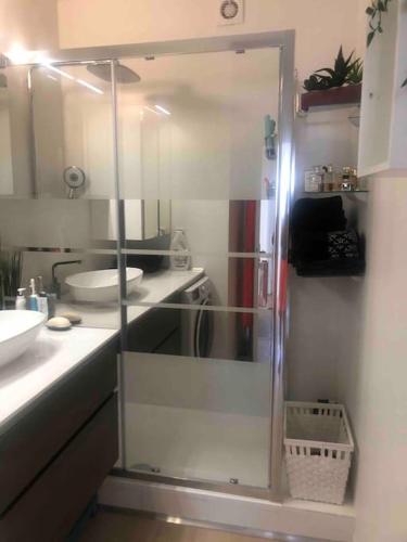 une salle de bain avec une douche en verre avec un lavabo dans l'établissement Antinéa Centre, Wifi, Plages et Climatisation, à La Grande Motte