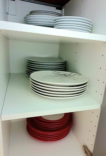 a stack of plates and bowls on a shelf at Rose Homestay Brighton - Free parking Ensuite studio room near Brighton Uni in Brighton & Hove