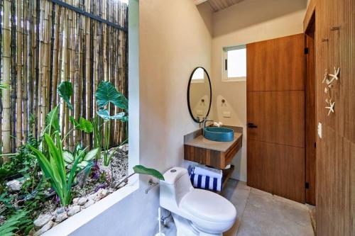 La salle de bains est pourvue de toilettes et d'une fenêtre avec une plante. dans l'établissement Tucán Studio Malpais, à Malpaís