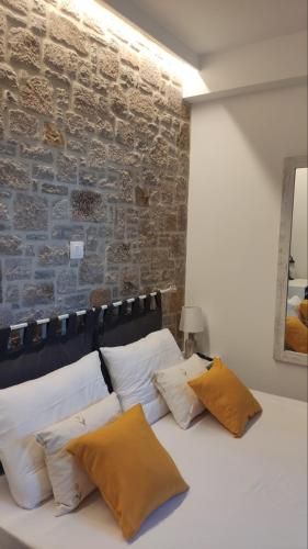 a bed with white pillows and a brick wall at Gea luxury apartment Myrina 1 in Myrina