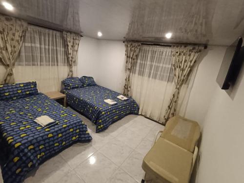 a room with two beds and a chair in it at Apartamento campestre Montaña Serena in Paipa