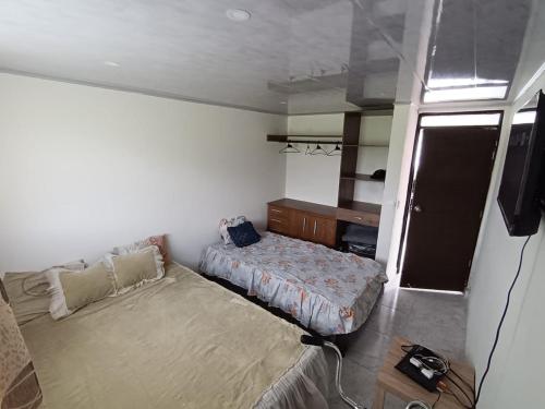 a small bedroom with a bed and a tv at Apartamento campestre Montaña Serena in Paipa