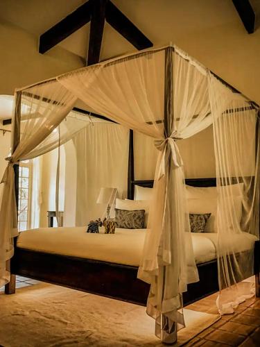 a bedroom with a canopy bed with white curtains at Raha Wildlife Resort in Arusha