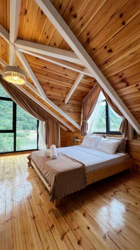 a large bed in a room with wooden ceilings at Hanging Garden Holiday Home - Riverside in Ardeşen
