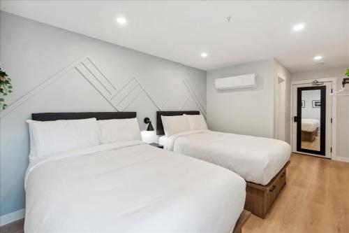 two beds in a bedroom with white walls and wood floors at The Oak Hotel in Nelson