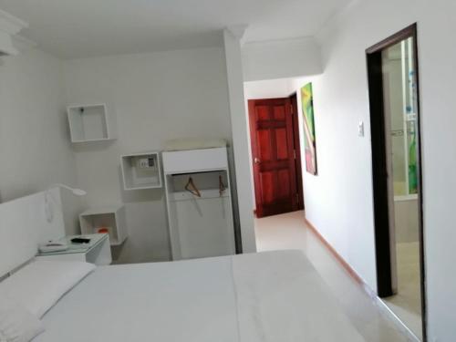 a white room with a red door and a kitchen at La Casa Blanca Hotel in Buenaventura
