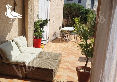 un balcon avec un canapé, une table et un cygne dans l'établissement La villa des goélands, au Barcarès