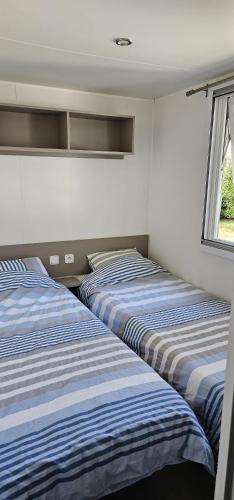 deux lits dans une chambre avec une fenêtre dans l'établissement Mobil home La palmyre 8 Pers, aux Mathes