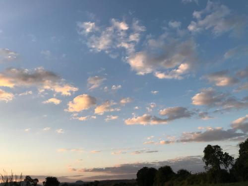 een bewolkte hemel bij zonsondergang met bomen in een veld bij The Reserve in Harare