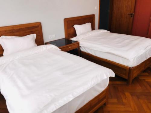 twee bedden met witte lakens in een kamer bij The Reserve in Harare